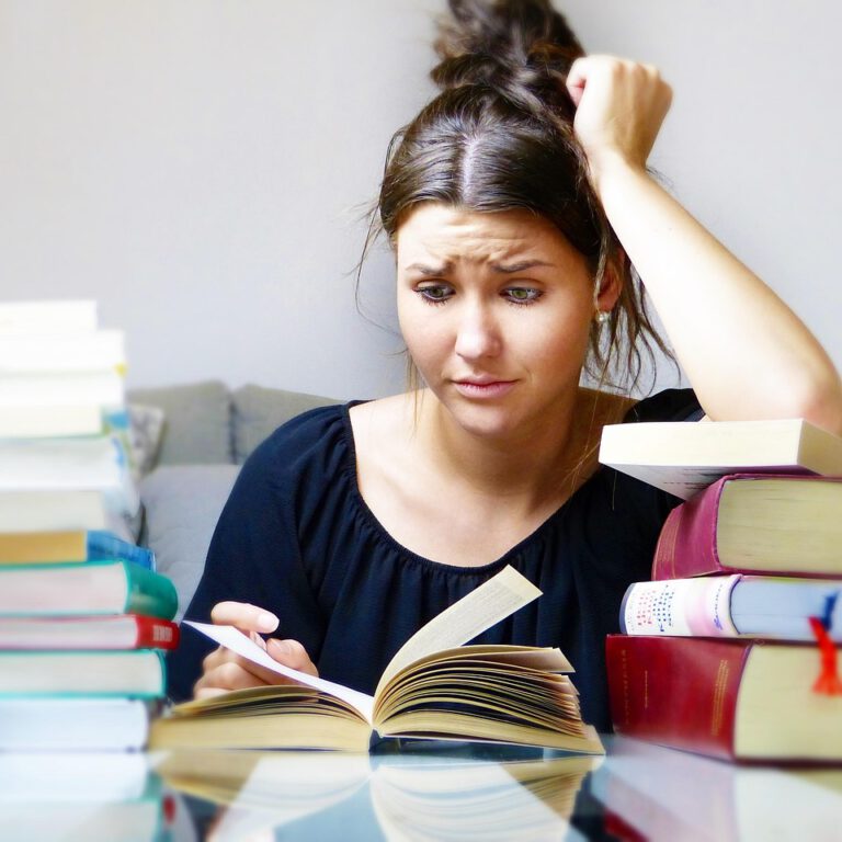 Mädchen sitzt zwischen Bücherbergen und sieht verzweifelt aus